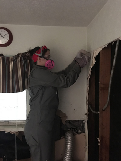 Amy Zachmeyer begins to tear down a wall damaged by Hurricane Harvey's floodwaters. (Photo: Houston DSA)