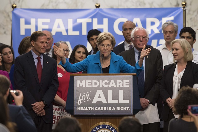 US Senator Elizabeth Warren (C), Democrat from Massachusetts, speaks with US Senator Bernie Sanders (2nd R), Independent from Vermont, as they discusses Medicare for All legislation on Capitol Hill in Washington, DC, on September 13, 2017. The former US presidential hopeful introduced a plan for government-sponsored universal health care, a notion long shunned in America that has newly gained traction among rising-star Democrats. / AFP PHOTO / JIM WATSON