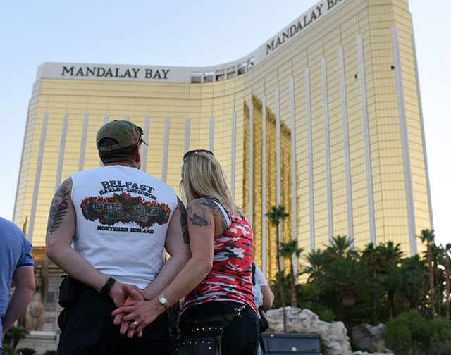 A couple stops on the Las Vegas Strip October 4, 2017, to look up at the two broken window in the Mandalay Bay hotel from which killer Stephen Paddock let loose the worst mass shooting in modern American history on October 1, 2017 at a country music festival across the street in Las Vegas, Nevada leaving 58 dead and over 500 injured. (Photo: ROBYN BECK / AFP / Getty Images)