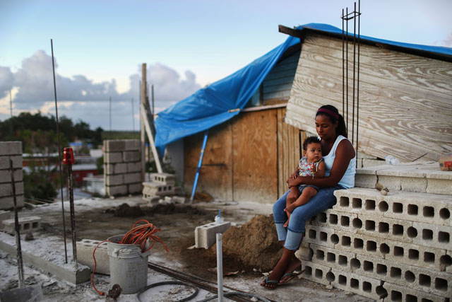 Mother Isamar holds her baby Saniel, 9 months, at their makeshift home, under reconstruction, after being mostly destroyed by Hurricane Maria, on December 23, 2017, in San Isidro, Puerto Rico. Their neighborhood remains without electricity. (Photo: Mario Tama / Getty Images)