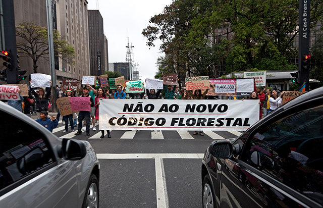 Environmental activists hold banners during a demonstration, in Sao Paulo, Brazil, on August 20, 2011, against the construction of Belo Monte dam at Xingu River, a tributary of the Amazon River in the northeastearn Brazilian state of Para. Belo Monte is planned to be the third largest hydroelectric plant in the world. The biggest banner reads 'No to the new forest code'. (Photo: YASUYOSHI CHIBA / AFP / Getty Images)