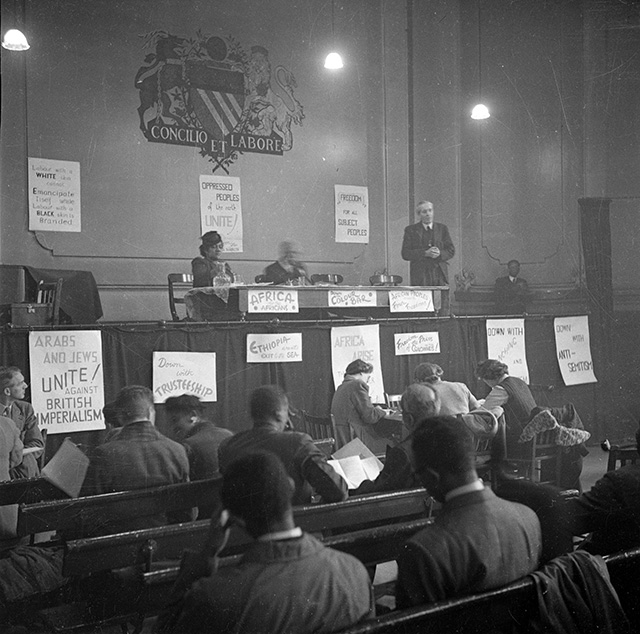 Amy Jacques Garvey, the second wife of Marcus Garvey, is seated on the stage as John McNair, General Secretary of the ILP (Independent Labour Party) addresses the first Pan-African Congress in Manchester. Original Publication: Picture Post - 3024 - Africa Speaks In Manchester - pub. 1945 (Photo: John Deakin / Picture Post / Getty Images)