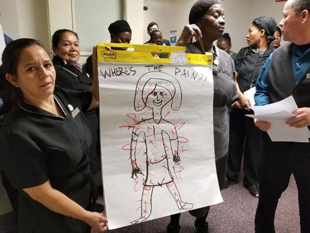 Stamford Hilton housekeepers deliver a poster to hotel management illustrating where their bodies feel pain due to excessive workloads as one of their daily actions. (Photo: Unite Here Local 217)