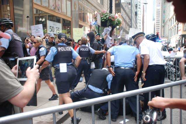 Chicago Police push two protestors down to the pavement prior to arresting them along with several other anti-ALEC activists. (Photo: James Anderson)