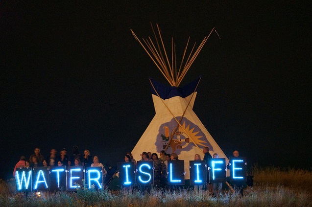 The Holders of the Light held several Idle No More water-related messages in front of the 2013 Indian Summer Festival's Tipi, prominently located on the State Park Island in front of the Indian Summer grounds. (Photo: <a https://www.flickr.com/photos/40969298@N05/9696047375/