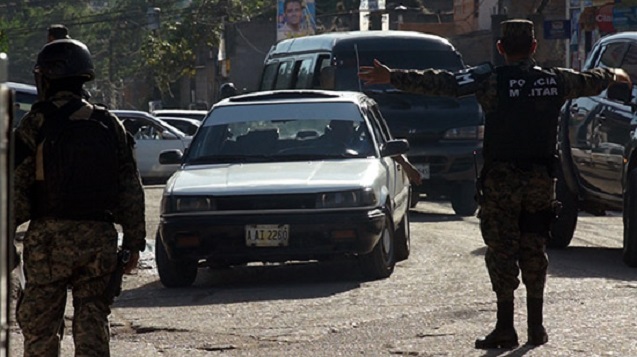 Military Police directing local traffic away from the area where the raid of activist Edwin Espinal’s Flor del Campo home was taking place. (Photo: Jesse Freeston)