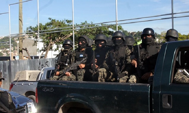 Military Police arriving to Edwin Espinal’s house in one of several pickup trucks. In the background is aluminum fencing surrounding the newly-privatized Flor del Campo community soccer field, and another military police truck with three dog cages. Two other military police vehicles also came loaded with dogs. (Photo: Jesse Freeston)