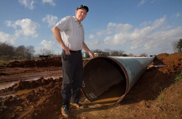 Michael Bishop stands in front of a section of the Keystone XL pipeline before it was installed on his property. (Photo: ©2013 Julie Dermansky)
