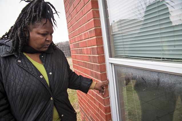 Melanie Williams inspects a new crack along the edge of a window. (Photo: © 2014 Julie Dermansky)