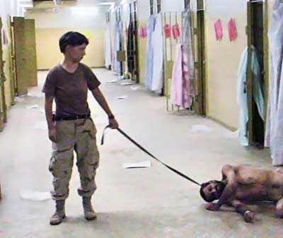 United States Army photo from Abu Ghraib prison in Iraq showing Pvt. Lynndie England holding a leash attached to a prisoner collapsed on the floor.