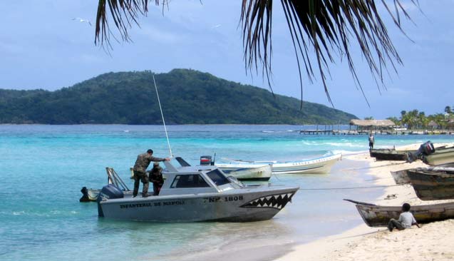 A Garifuna boy sits next to a traditional dugout canoe, watching a naval patrol boat arriving at Chachahuate. (Photo: Sandra Cuffe)