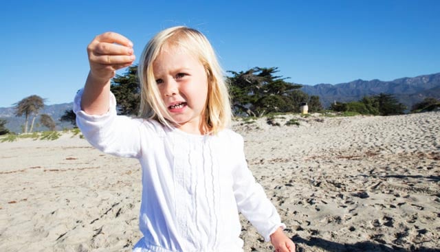 Three-year-old Hazel stops to inspect a piece of beach debris. 
