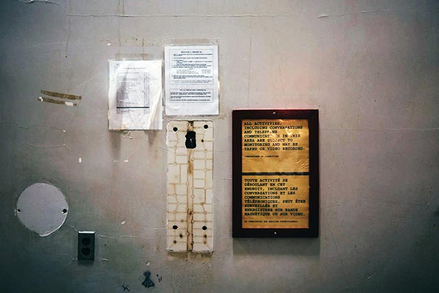 Access: the removal of a payphone from the wall during the decommissioning process leaves behind a rectangular outline. A list of phone numbers for outreach organizations and a bilingual sign warning inmates their calls may be recorded remain. (Photo: Cindy Blažević)