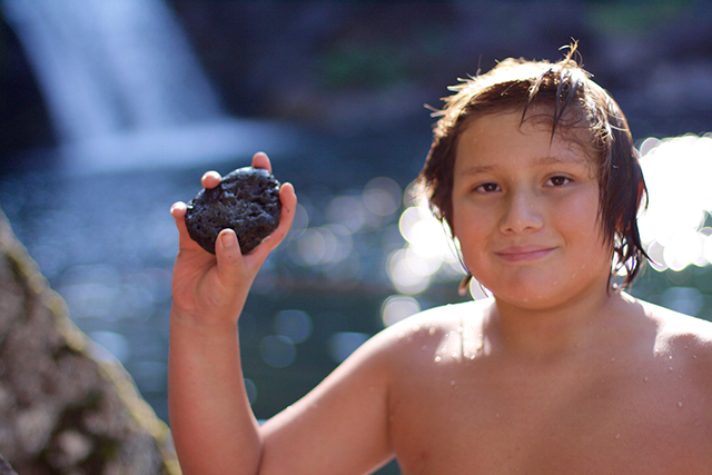  “Whatever happens to the salmon, happens to us” believe the Winnemem. When Shasta Dam was built, both the Winnemem and the salmon lost their homes on the river. Here, Brandon, a young Winnemem member holds a rock he grabbed from the riverbed in the upper falls of the McCloud River as part of the salmon challenge. (Rucha Chitnis)