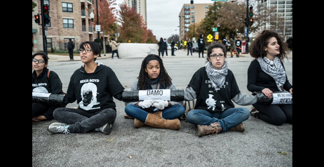 Protesters sit linked together with lockboxes, inscribed with the names of Damo and Rekia Boyd. (Photo: Sarah Jane Rhee)