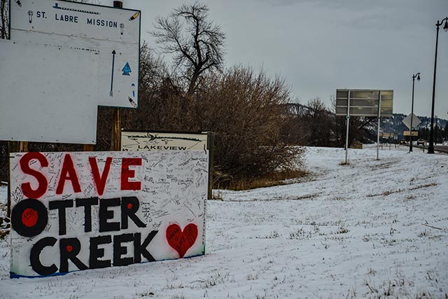 A Save Otter Creek sign placed at the main intersection in Lame Deer, Montana, on the Northern Cheyenne Reservation. (Photo by Alexis Bonogofsky)