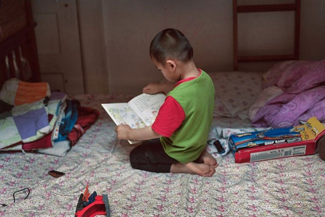  Ivy Gao's son Sampson, 3, reads in their unit in a Chinatown single-room occupancy hotel. (Photo: Tudor Stanley)