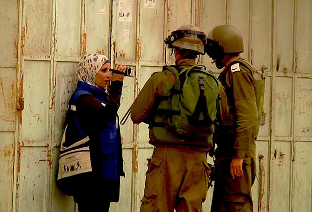 Working under the auspices of B'Tseleme's 'Camera Project,' a Palestinian woman films two Israeli soldiers. (Photo: In The Image)