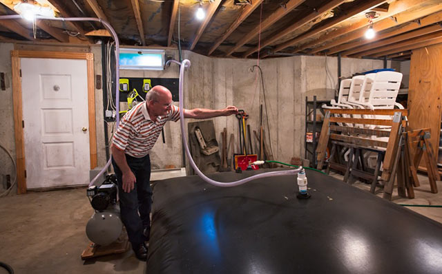 Andrew Chichura with a water bladder in his basement supplied by Cabot Oil. (Photo: ©2015 Julie Dermansky)