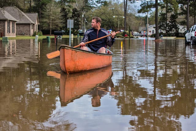 Man paddles down a street in the Tallow Creek subdivision in Covington. (Photo: © 2016 Julie Dermansky)