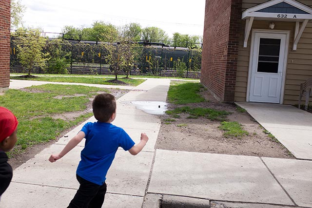 Antonio, five years old, runs through the complex with a friend, as a line of tanker cars sits feet away. (Photo: Earthjustice)