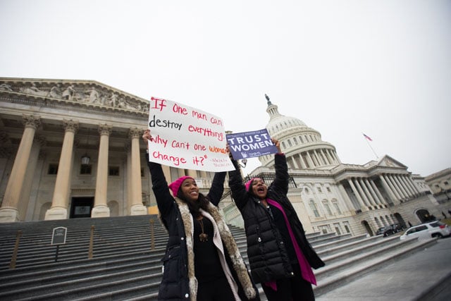 Camille and Tammy Jackson wave signs on the steps of the US Capitol Building, to cheers from the incoming Women's Marchers. (Photo: Zach Roberts)
