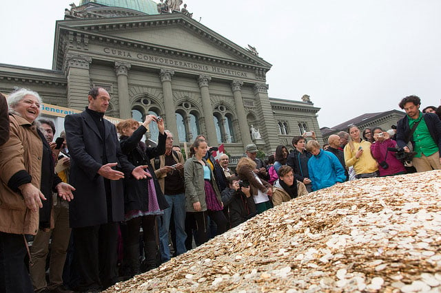 Supporters of the Swiss referendum to add universal basic income to the Swiss constitution watch as activists pour eight million valid Swiss 5-cent coins into the Bundesplatz to celebrate gathering enough signatures in Bern, Switzerland, on October 4, 2013. (Photo: Generation Grundeinkommen)