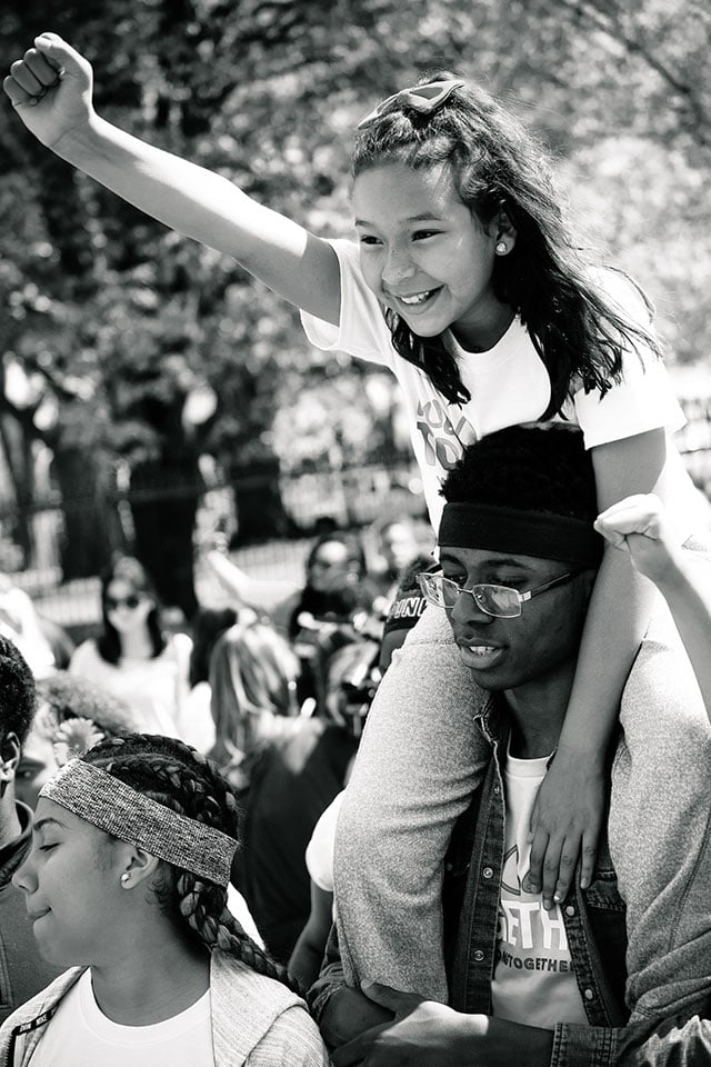 Washington, DC, April 13, 2017: Leah raises a fist on the shoulders of fellow We Belong Together Kids Caravan rider, Thomas, after their final action in front of the White House. Leah joined the caravan in part to fight for the dignity and rights of her undocumented mother, who is employed as a domestic worker in Miami. (Photo: Steve Pavey)