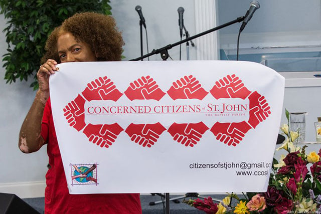 Lydia Gerard, a member of the Concerned Citizens of St. John, holding up a new sign at their public meeting on August 15.