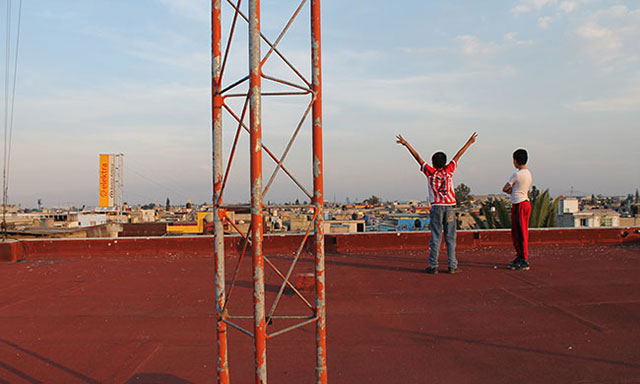 Two neighborhood kids stand on the roof of El BANCO.