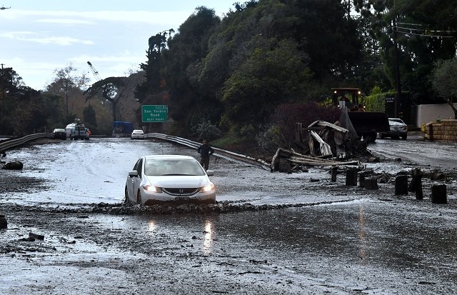 A vehicle drives across a flooded US 101 freeway near the San Ysidro exit in Montecito, California on January 9, 2018. Mudslides unleashed by a ferocious storm demolished homes in southern California and killed at least 13 people, police said Tuesday. (Photo: FREDERIC J. BROWN/AFP/Getty Images)
