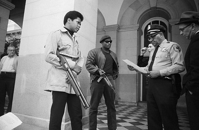 Two members of the Black Panther Party are met on the steps of the State Capitol in Sacramento, May 2, 1967, by Police Lt. Ernest Holloway, who informs them they will be allowed to keep their weapons as long as they cause no trouble and do not disturb the peace. Earlier several members had entered the Assembly chambers and had their guns taken away.
