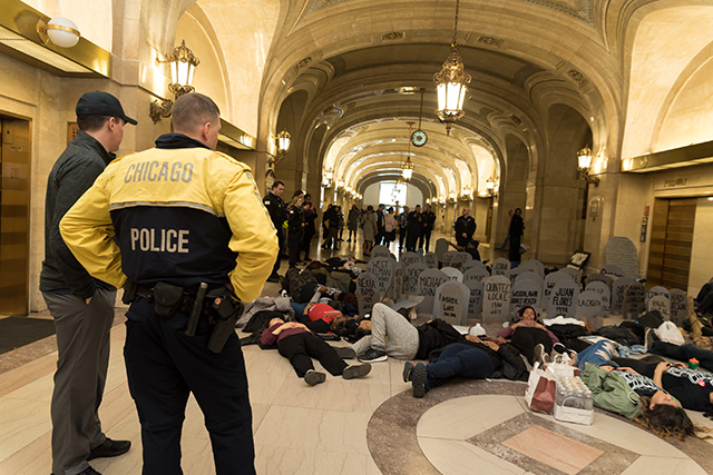 Police watch as Chicago students die-in at City Hall in protest of Rahm Emanuel's proposed police training facility. (Photo: Sarah-Ji)