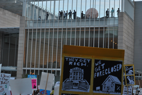 Mortgage bankers on roof, with protest sign.