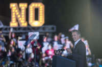 Gavin Newsom speaks in front of a huge sign reading "NO"