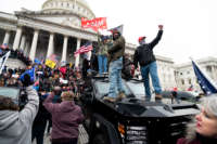 Trump supporters stand on a U.S. Capitol Police armored vehicle as others take over the steps of the Capitol on January 6, 2021, as the Congress works to certify the electoral college votes.