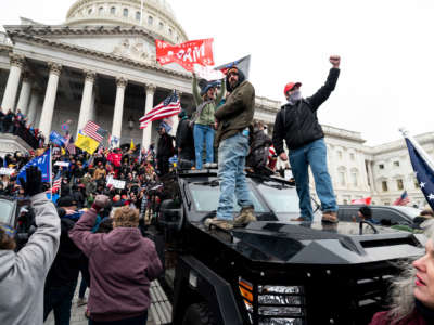 Trump supporters stand on a U.S. Capitol Police armored vehicle as others take over the steps of the Capitol on January 6, 2021, as the Congress works to certify the electoral college votes.