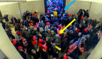 A screenshot of security footage from the U.S. Capitol on January 6, 2021, included in the charging documents filed against Jessica Watkins. Watkins is indicated by the yellow arrow.