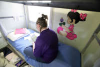 A young inmate at Illinois Youth Center at Warrenville, the state's maximum-security prison for girls, reads on her bed next to a mural on her bedroom wall on June 27, 2007.