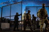 Members of the National Guard walk through a security fence surrounding the U.S. Capitol Building on March 4, 2021, in Washington, D.C.