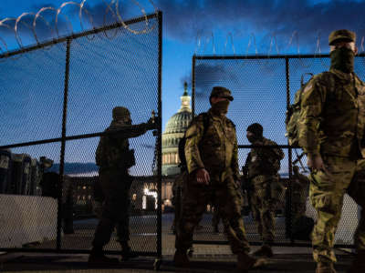 Members of the National Guard walk through a security fence surrounding the U.S. Capitol Building on March 4, 2021, in Washington, D.C.