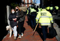 Girls walking a dog down Joy Street react as they pass by hundreds of Boston Police officers, who arrived in busses on Beacon Street and made their way towards the Massachusetts State House ahead of concerns over a protest by far right groups in Boston on January 17, 2021.