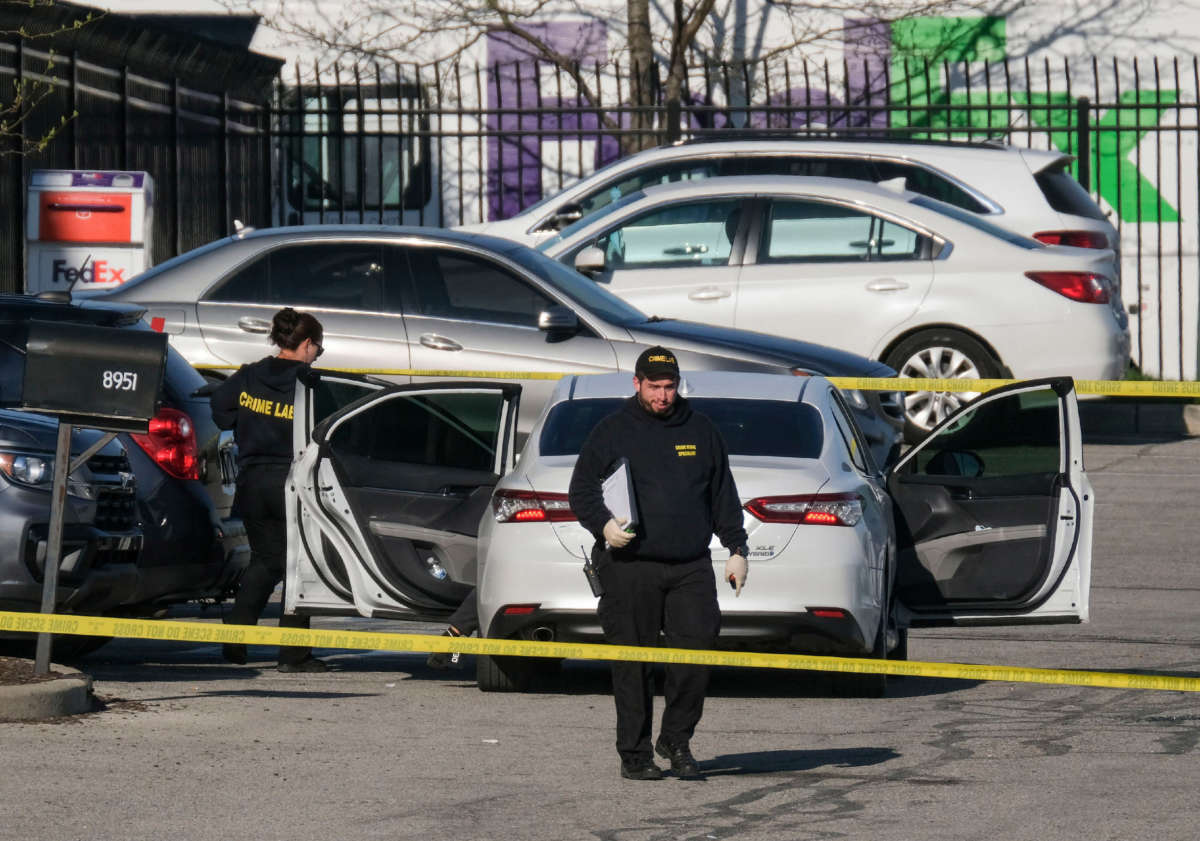 Crime scene investigators walk through the parking lot of the mass shooting site at a FedEx facility in Indianapolis, Indiana, on April 16, 2021.