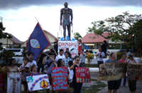 People demonstrate in front of a statue Chief Quipuha