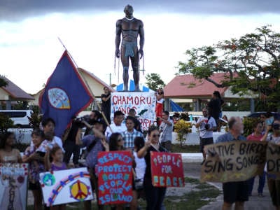 People demonstrate in front of a statue Chief Quipuha