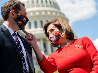Speaker of the House Nancy Pelosi checks out the mask of Rep. Jason Crow during a news conference outside the Capitol on May 13, 2021.
