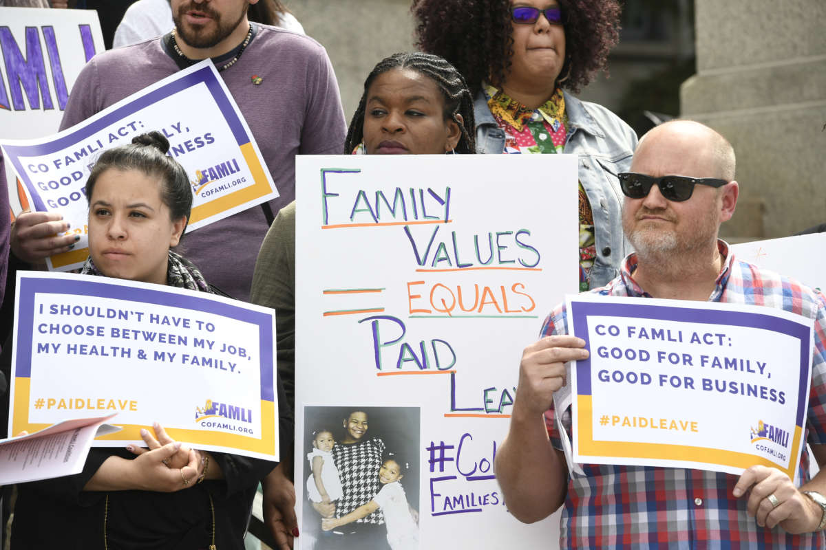 Parents display signs calling for paid parental leave during a protest