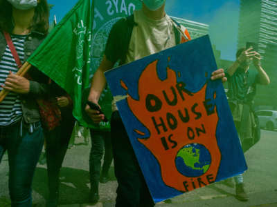 A protester holds a placard reading "Our house is on fire" during a climate demonstration outside the Hague, Netherlands, on June 24, 2021.