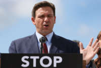 Ron DeSantis speaks at a podium that reads "STOP"