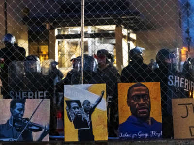 Elijah McClain and George Floyd pictures left by demonstrators line up the fence outside the Brooklyn Center police station while protesting the death of Daunte Wright, who was shot and killed by a police officer, in Brooklyn Center, Minnesota, on April 14, 2021.